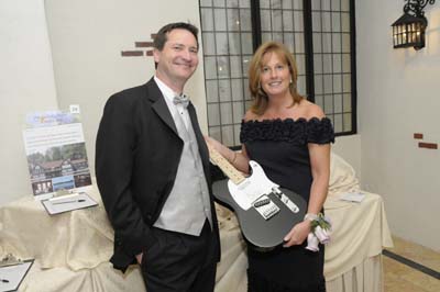 Kathleen Townshend Dugan, chair of the Alzheimers Association Greater New Jersey Chapter 2012 Memories Should Last a Lifetime annual benefit gala, and association board vice chair, stands with husband Peter while showcasing a guitar autographed by Bruce Springsteen, one of the choice silent auction items for the evening, which took place on Friday, March 23, 2012, at the Pleasantdale Chateau in West Orange.  Photo courtesy of Ray Silva, Citywide Photography